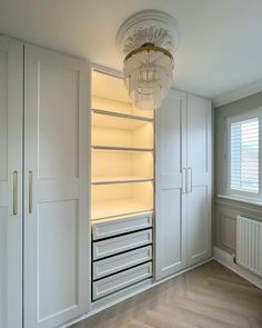 an empty room with white cupboards and lights on the ceiling is lit by a crystal chandelier