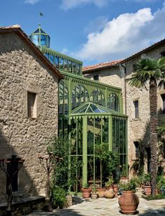 an old building with a green glass door and windows on the outside, surrounded by potted plants