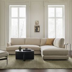 a living room with two couches and a coffee table in front of three windows