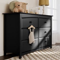 a black dresser with a teddy bear on top