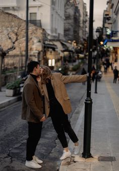 a man and woman standing next to a street light on the side of a road