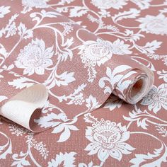 a pink and white floral wallpaper with rolled up paper on the bottom right corner