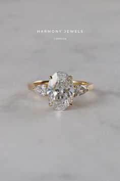 an oval cut diamond ring with three pear shaped diamonds on the band and side stones