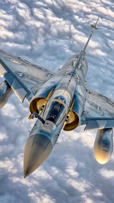 a fighter jet flying through the sky above clouds