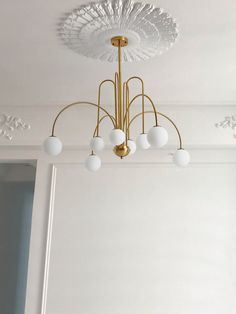 a chandelier hanging from the ceiling in a room with white walls and flooring