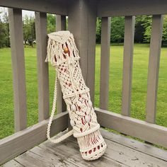 a white crocheted umbrella sitting on top of a wooden deck next to a green field