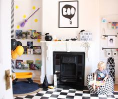 a child sitting on a chair in front of a fireplace with halloween decorations around it