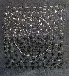 an embroidered piece with small white crosses on black fabric, in the shape of a circle