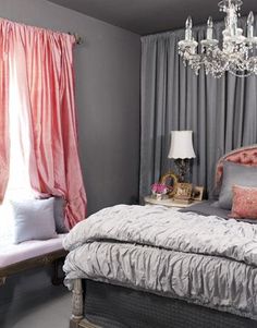 a bedroom decorated in gray and pink with a chandelier hanging from the ceiling