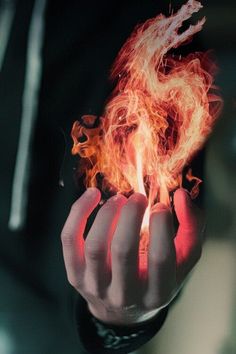 a person holding out their hand with fire in the middle of it's fingers