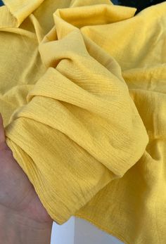 a hand holding a piece of yellow cloth in it's left hand, with the fabric partially folded up