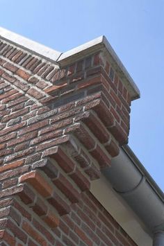 the corner of a brick building with a bird perched on it's roof top