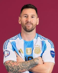 a man with his arms crossed standing in front of a red background wearing a blue and white shirt