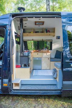 the interior of a van with its door open and shelves on the wall, in front of trees