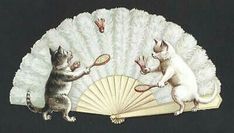 two cats are playing with each other on a white fan and holding tennis racquets