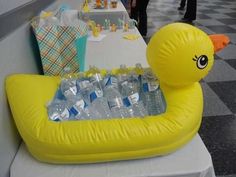 an inflatable rubber ducky filled with bottled water sits on a long table