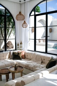 a living room filled with lots of white furniture and large windows overlooking an outdoor swimming pool