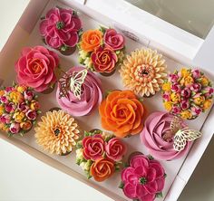 the cupcakes in the box are decorated with colorful flowers and butterfly decorations on them