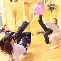 three children are playing with a pink ball in the middle of a dance floor while another child watches