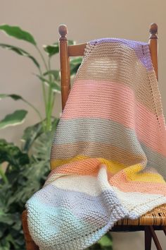 a chair with a blanket on it next to a potted plant