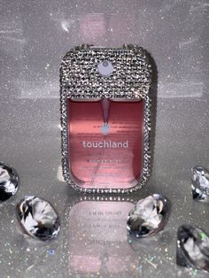 a cell phone with diamonds surrounding it on a silver surface, surrounded by other jewels