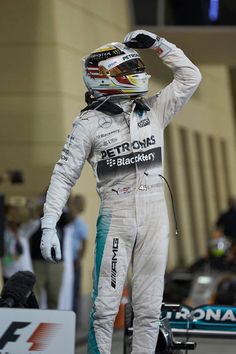 a man standing on top of a race car holding his hand up in the air