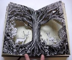 an open book with two deer cut out of it's pages and trees on the inside