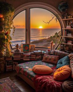 a living room filled with furniture and a large window overlooking the ocean at sunset or sunrise