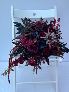 a bouquet of flowers sitting on top of a white chair with red and purple flowers