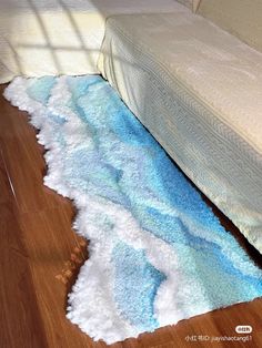 a bed sitting on top of a hard wood floor next to a rug covered in blue and white waves