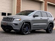 a gray jeep parked in front of a garage