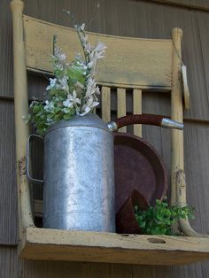 a metal bucket with flowers in it sitting on a wooden chair