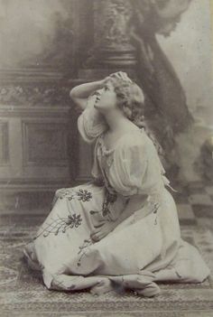 an old black and white photo of a woman sitting on the ground with her hands behind her head