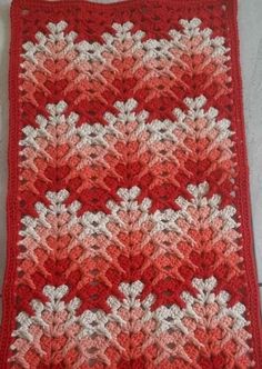 a red and white crocheted afghan with snowflakes on the edges is shown