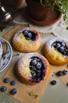 three blueberry donuts are sitting on a table next to a cup of coffee