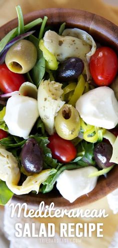 a salad with olives, tomatoes and mozzarella cheese in a wooden bowl