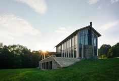 the sun shines brightly behind a building on top of a grassy hill with stairs leading up to it