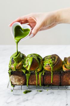 someone is pouring green sauce on some bread