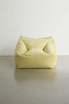 a large yellow bean bag chair sitting on top of a cement floor next to a white wall