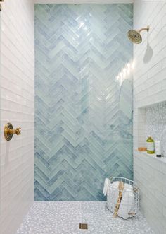 a bathroom with blue and white tile on the walls, shower head, and tub