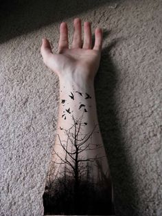 a person's arm with a tree and birds on it
