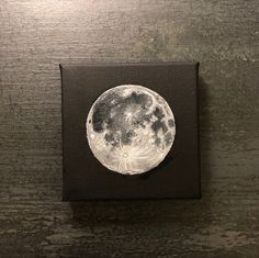 a black and white photo of the moon on a wooden table with dark wood grains