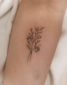 a small flower tattoo on the left side of the right arm, with tiny flowers growing out of it