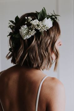 a woman with flowers in her hair wearing a white dress and a flower crown on her head