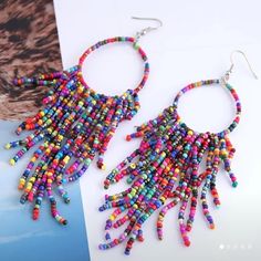 colorful beaded earrings are displayed on top of a magazine page and in front of a photograph