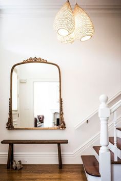 a mirror sitting on top of a wooden bench next to a stair case in a room