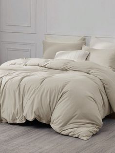 an unmade bed with beige sheets and pillows