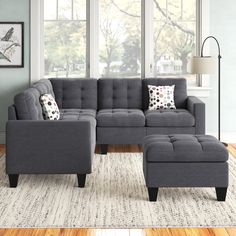 a living room with a gray sectional couch and footstool in front of a large window