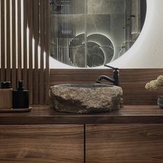 a bathroom sink sitting under a mirror on top of a wooden counter next to a vase with flowers