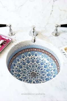 a blue and white sink sitting on top of a counter next to a faucet